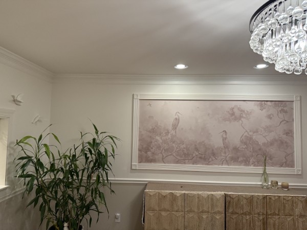 Dining area with a soft heron mural, woven sideboard, and bubble-glass chandelier