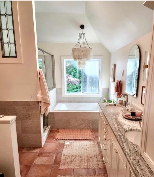 Primary bath with a soaking tub, beaded chandelier, and warm terracotta rugs