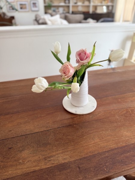 Tabletop vignette with pink roses and white tulips in a handmade bud vase